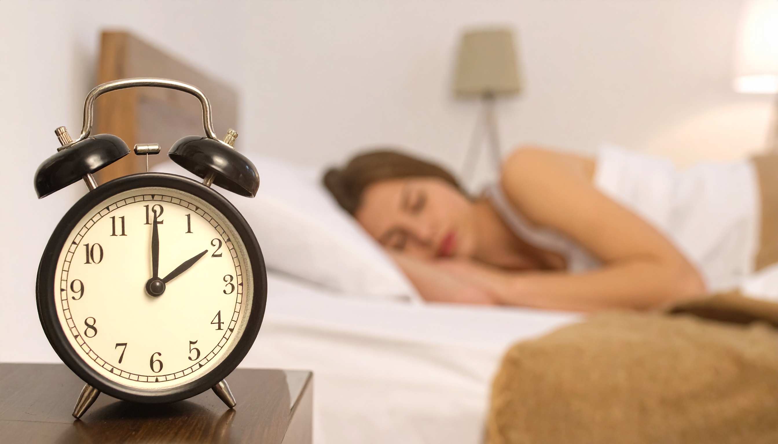alarm clock showing early morning time with person sleeping peacefully behind it - Steve's Goods