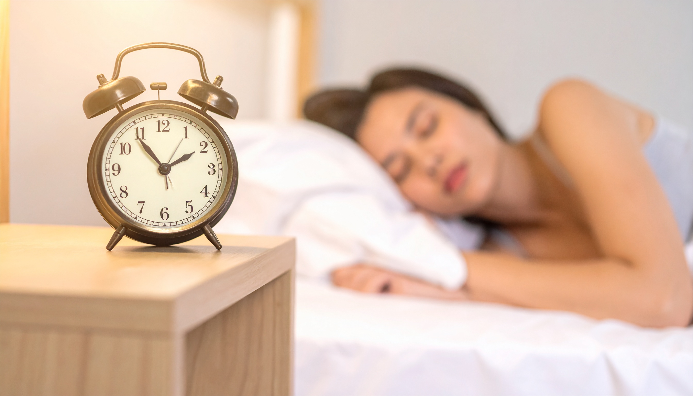 alarm clock showing early morning time with person sleeping peacefully behind it - Steve's Goods