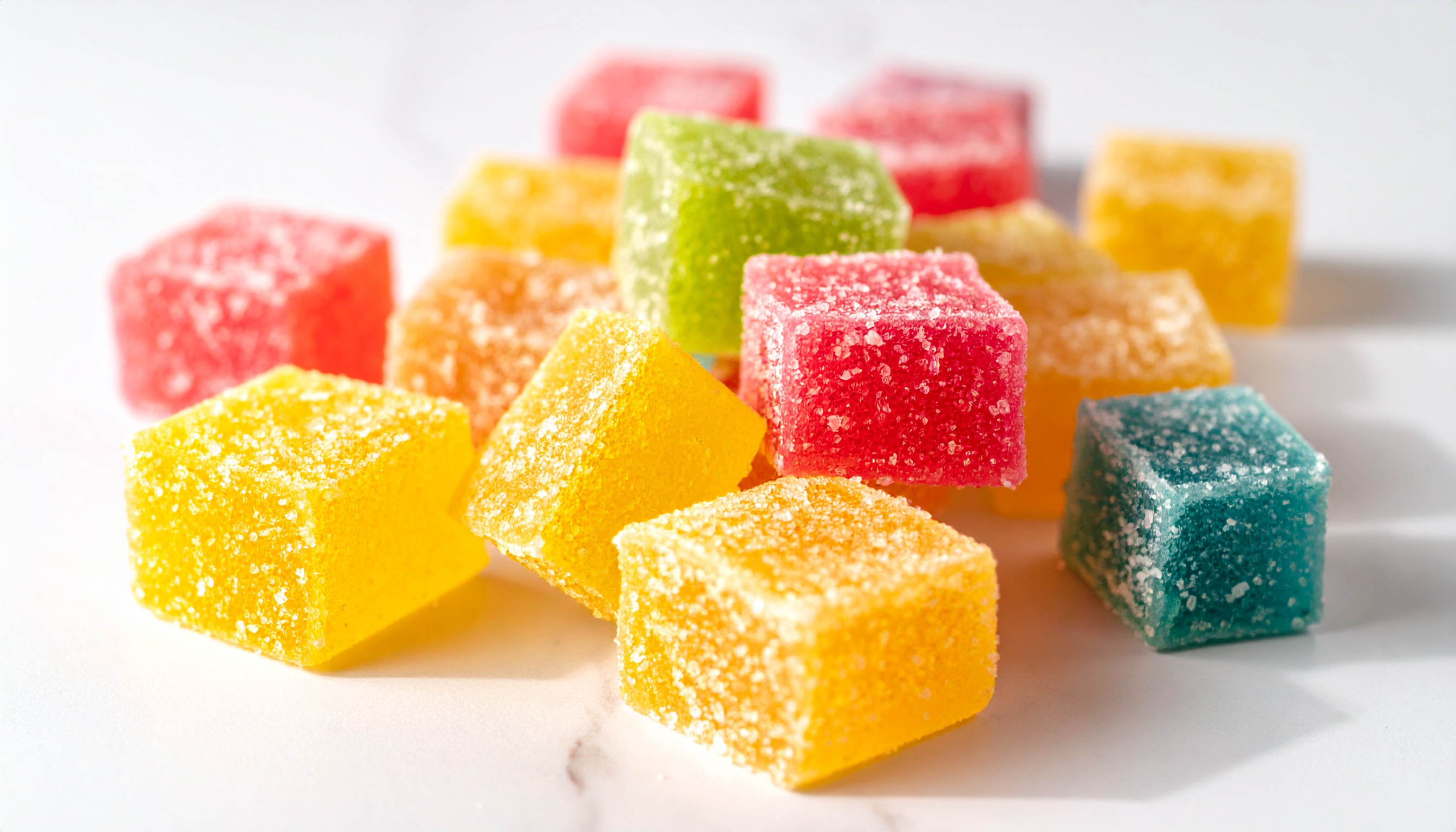close up of colorful cube shaped sugar coated vegan gummies arranged on a clean  - Steve's Goods
